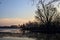 Skyline of a town seen from the distance over a lake at sunset framed by trees