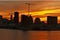 A skyline view of a city with a lifting crane in a construction site in the middle and a foreground a river