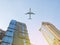 Skyscraper facades on a bright sunny day with sunbeams in the blue sky and passenger aircraft flying over it