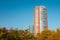 Skyscraper or flat block building on clear blue sky and autumn trees background. Closeup view with copy space. Modern urban