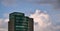 Skyscraper with a glass facade against the backdrop of a large white cloud in the evening sky