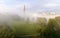 Skytrain bridge by a riverside park in a foggy morning