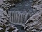 SkÃ³gÃ¡ river with waterfall Steinbogafoss in a rocky canyon near FimmvÃ¶rÃ°uhÃ¡ls trail in winter with rocks in Iceland.