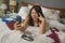 Slackness and chaos at home lockdown - young disorderly and chaotic Asian Chinese woman on bed taking selfie with mobile phone on