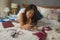 Slackness and disorganized during covid-19 home lockdown - young disorderly and chaotic Asian woman on bed using internet mobile