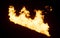 Slanted line of large Flames with a light reddish glow on dark