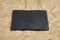 Slate board on crumpled craft paper background. Empty black stone serving board
