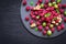 Slate dish with different berries. Raspberries, gooseberries, currants on a black background