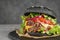 Slate plate with black burger on table, closeup