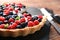 Slate plate with delicious berry pie on wooden table, closeup