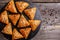 Slate plate with delicious samosas on rustic background, top view