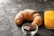 Slate plate with fresh crescent roll, glass of juice and bowl with chocolate on table