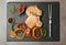 Slate plate with grilled meat, garnish and sauce on grey background