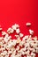 Slaty popcorn scattered on red background, top view