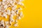 Slaty popcorn scattered on yellow background, top view