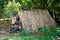 A slave sitting in front of a straw house