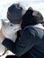 Sled Siberian Husky carefully and  attentively sniffing the young guy in dark grey hat, who hugs the dog