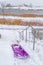 Sled on snow with lake and homes in the background