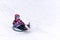 A sledding little girl on a hill against a winter landscape