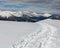 Sledge trace and footprints on winter mountain hill top