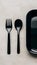 Sleek, minimalist trio black fork, spoon, rectangular tray on neutral background