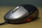 Sleek silver and black computer optical mouse with red light glowing against wooden desk table