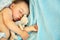 Sleeping baby with a soft toy bear. little boy lying in crib on a blue blanket