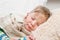 Sleeping boy lying in bed with a thermometer in mouth