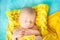 Sleeping cute newborn baby on a yellow chunky knit blanket