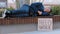 Sleeping homeless fired African American man male sleep on bench in city with poster need work. Lonely upset ethnic guy