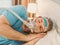 Sleeping man with chronic breathing issues considers using CPAP machine in bed.