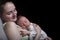 Sleeping mother with a sleeping baby on her chest, a moment of tenderness. Black background, space for text