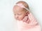 Sleeping newboen baby in a pink wrap