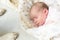 Sleeping newborn baby with beagle dog next to her. Cute little girl one week old. Adorable lying on side covered with blanket