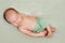 Sleeping newborn baby in green pants with crossed legs