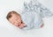 Sleeping newborn baby swaddled in a light blue wrap