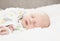 Sleeping Newborn in Comfortable Sleeper Pajamas on a White Soft