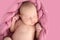 Sleeping newborn girl on coral pink background