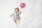 Sleeping newborn girl in a dress. White sheet, pink balloon in hand. Top view. Places for text