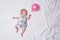 Sleeping newborn girl in a dress. White sheet, pink balloon in hand. Top view. Places for text