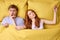 sleeping problems and people concept - unhappy man lying in bed with redhead woman disturbing him to sleep