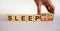 Sleepless or sleep well. Male hand flips wooden cube and changes words `sleepless` to `sleep well`. Beautiful white background