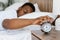 Sleepy Black Man Turning Off Alarm Clock Lying In Bed