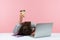 Sleepy bored woman office worker lying on table with laptop holding and showing paper coffee cup, feeling lack of energy sitting