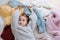 Sleepy little girl is lying on a pile of soft multi-colored sweaters on the floor