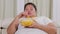 Sleepy obese woman eats popcorn on the couch