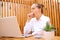 Sleepy overworked woman wearing white shirt sitting in outdoor cafe working on laptop yawning needs rest covering mouth with fist