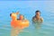 Sleepy toddler boy on inflating ring swimming with mom in sea