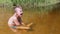 A Sleepy Yawning Child Sits in a Lotus Position in a Shallow River at Sunset. 4K