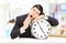 Sleepy young businessman leaning his head on a big wall clock, i